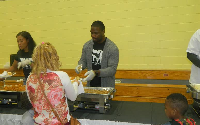 Jameel McClain hands out food at his 53 Families Thanksgiving event.