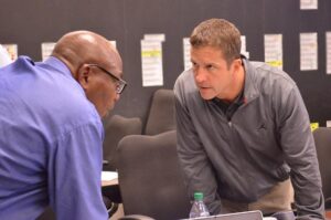 John Harbaugh and Ozzie Newsome leaning in to talk in the Ravens War room.