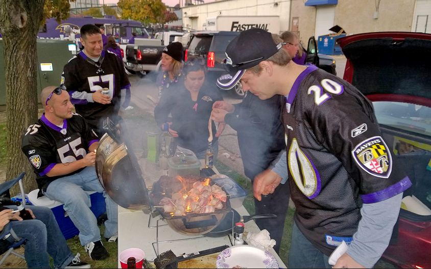 Baltimore Ravens fans tailgate at a grill.