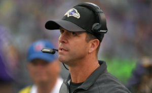 John Harbaugh, wearing a dark grey shirt, a black hat and his headset on the sideline when the Ravens played the Seahawks on 12/13/15