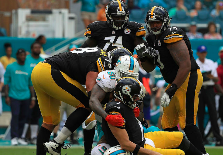 A Dolphins player sacks Ben Roethlisberger as Steelers offensive lineman look on.