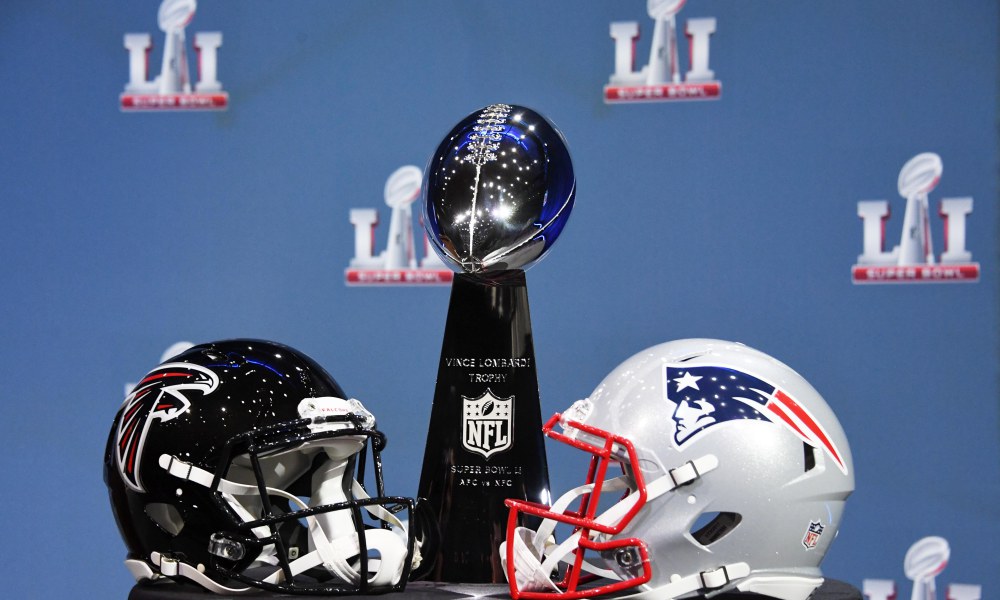 Patriots and Falcons helmets around the Super Bowl trophy.