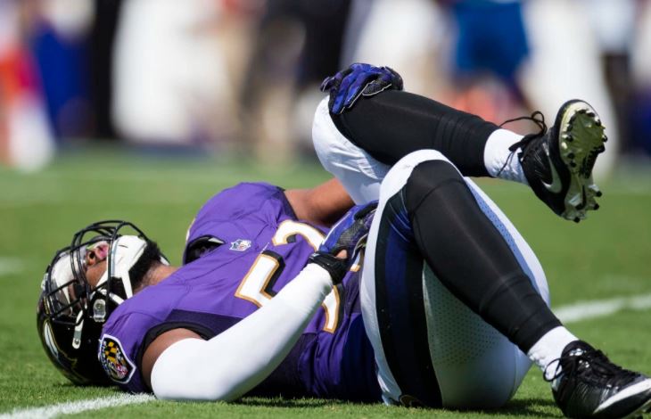 Bam Bradley of the Ravens holds his knee in pain on the turf.