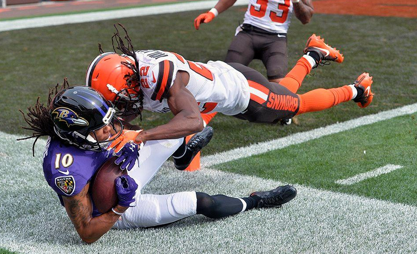 Chris Moore of the Ravens makes a catch on the sideline as Browns tackle him.