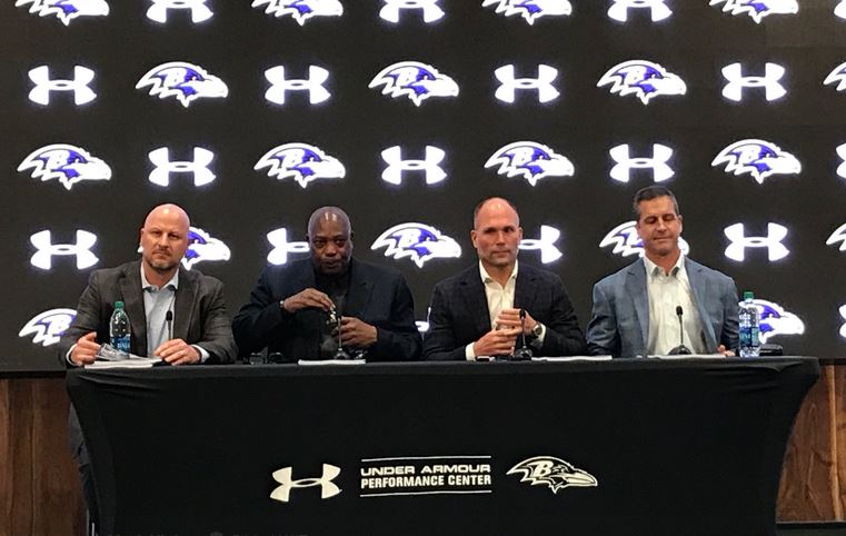 Joe Hortiz, Ozzie Newsome, Eric DeCosta, and John Harbaugh at a table in the Ravens press room.