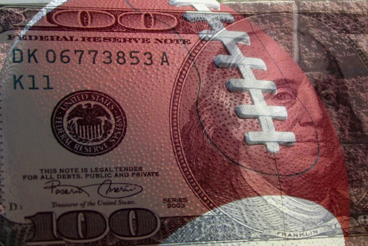 Transparent football overlaying a one hundred dollar ($100) bill