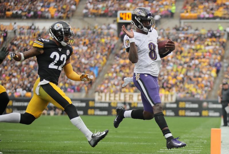 Lamar Jackson steps out of bounds as a Steelers defender chases.