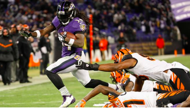Alex Collins carries the ball past Bengals defenders.